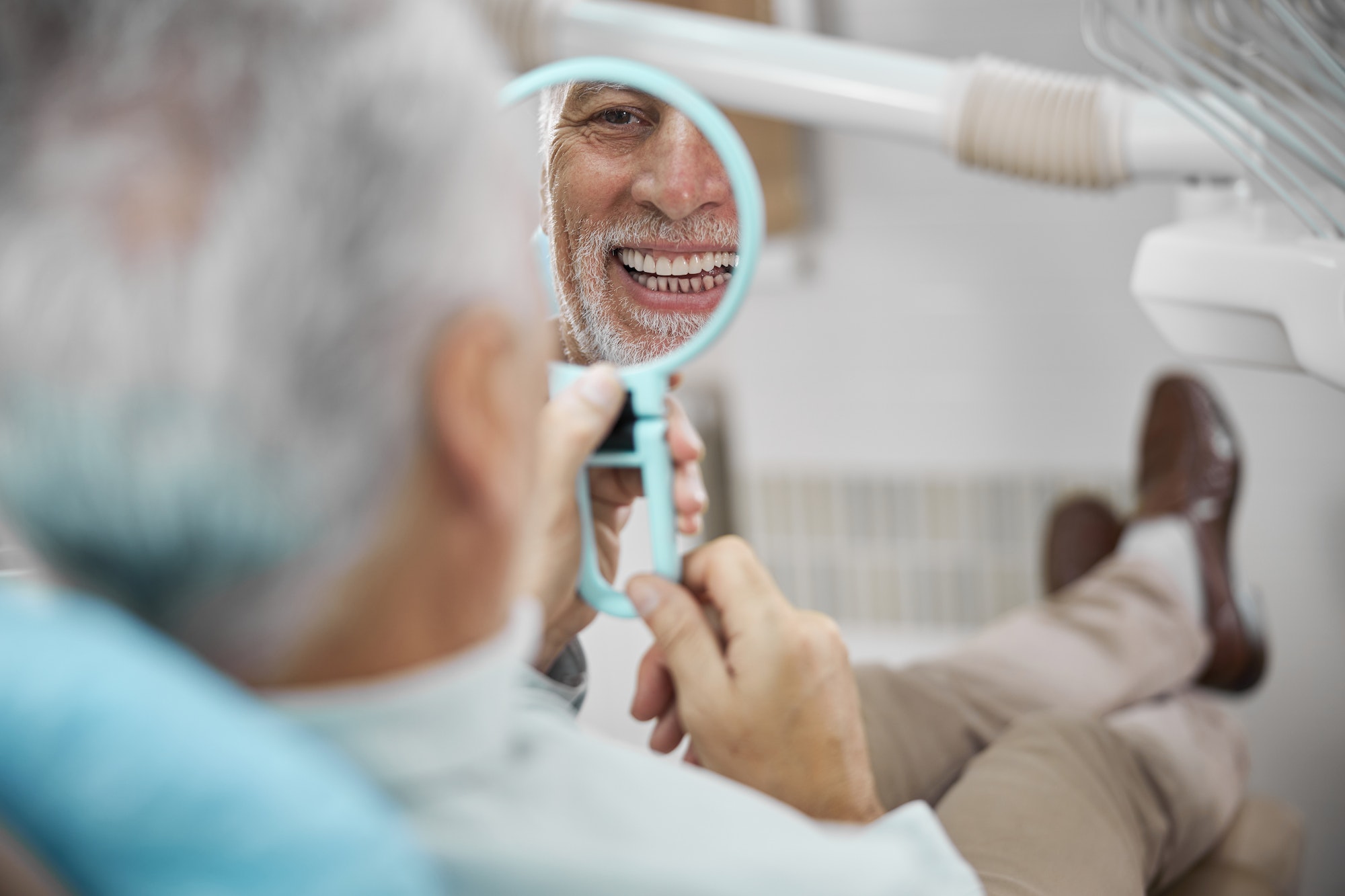 Eldelry man looking in the mirror and smiling TranscenDental Smiles provides PERIODONTAL GUM DISEASE THERAPY in houston texas
