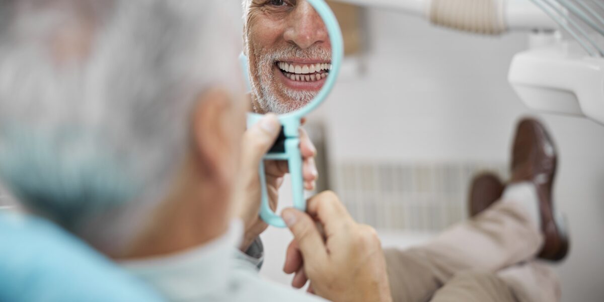 Eldelry man looking in the mirror and smiling TranscenDental Smiles provides PERIODONTAL GUM DISEASE THERAPY in houston texas