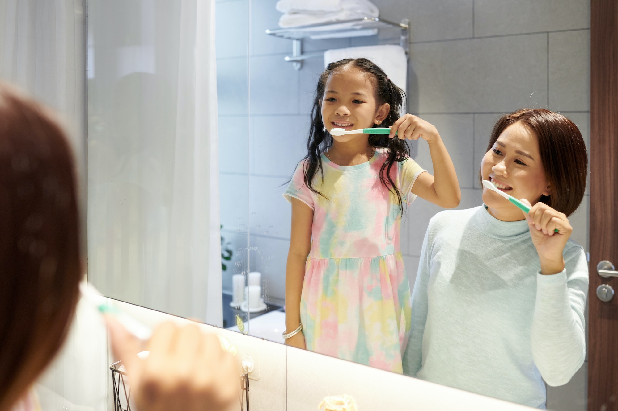 Mother and daughter brushing teeth Book and appointment with TranscenDental Smiles for your tooth extraction