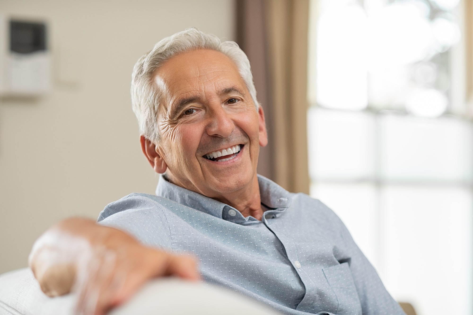 Senior man smiling at home TranscenDental Smiles is a great dentist to see about porcelain veneers.