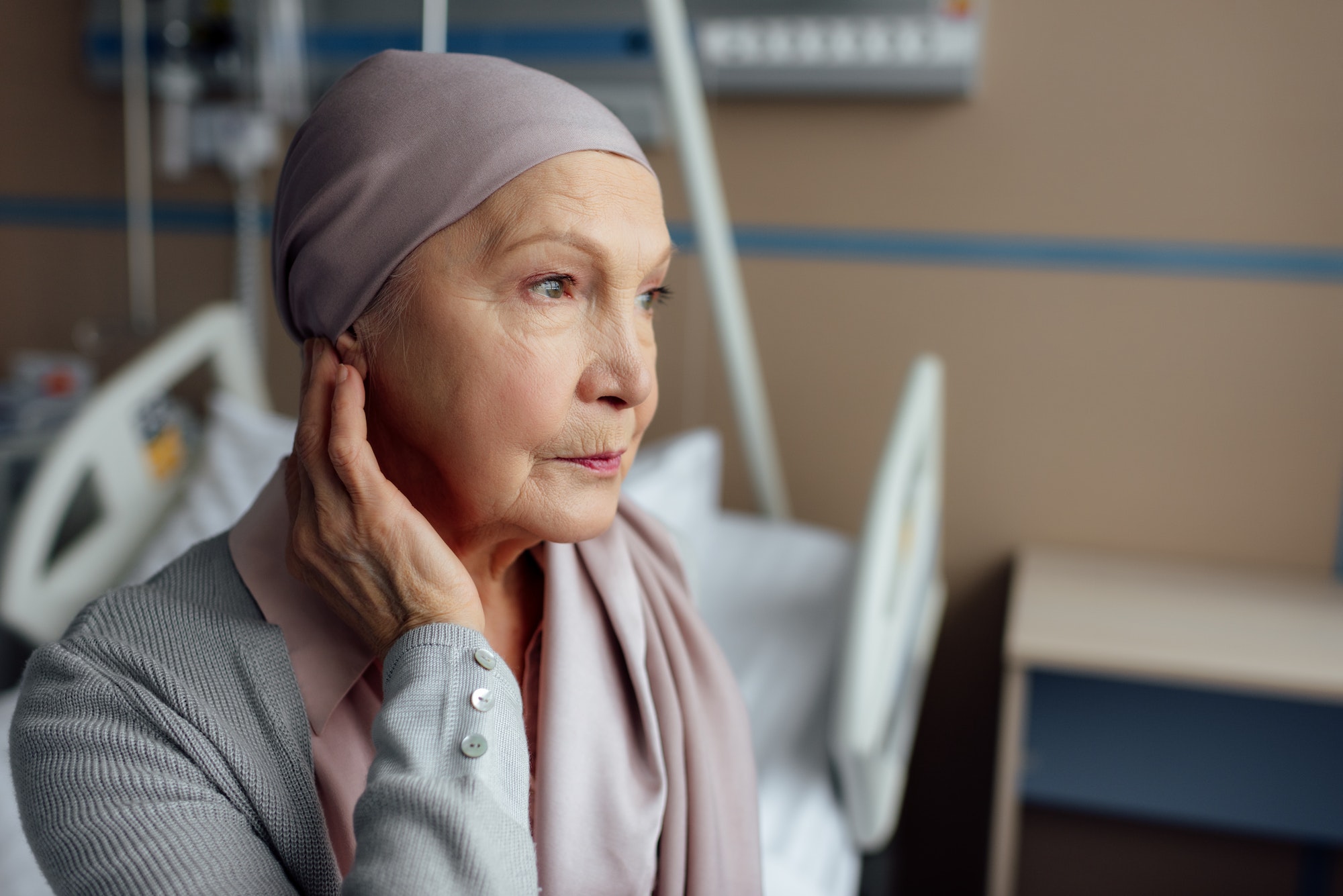 upset senior woman with cancer sitting on bed in hospital TranscenDental Smiles Provids ORAL CANCER SCREENING services